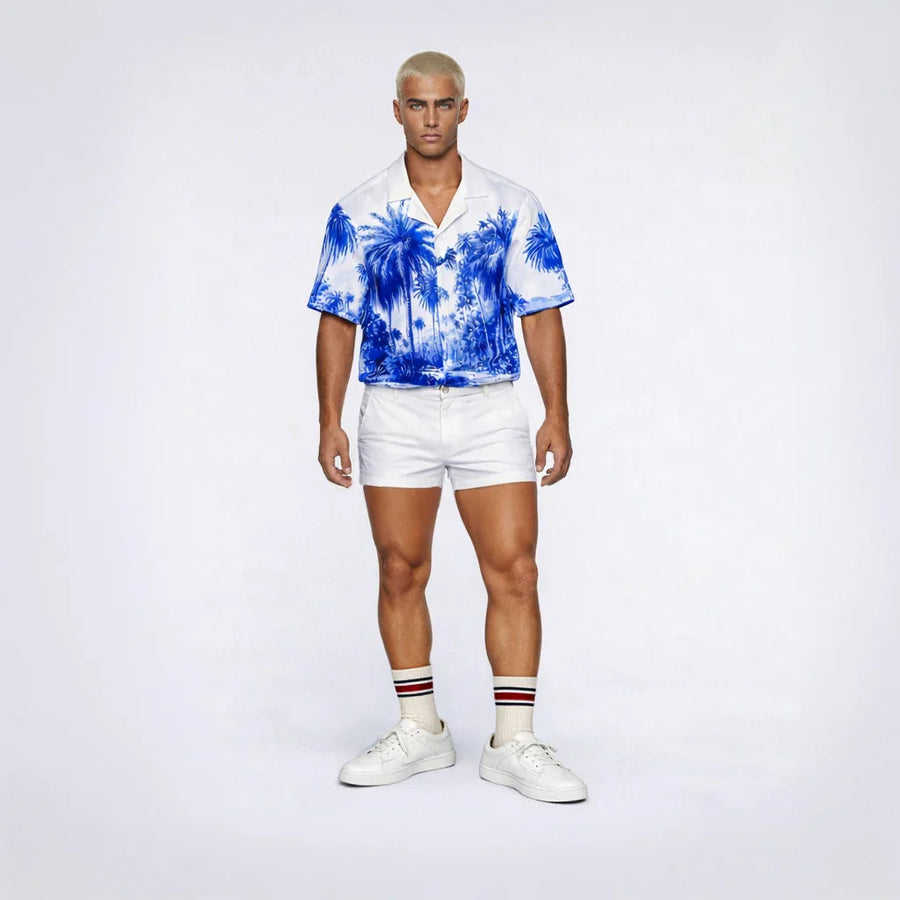 Model wearing the Palm Stallion Blue Jungle men's revere shirt with white shorts